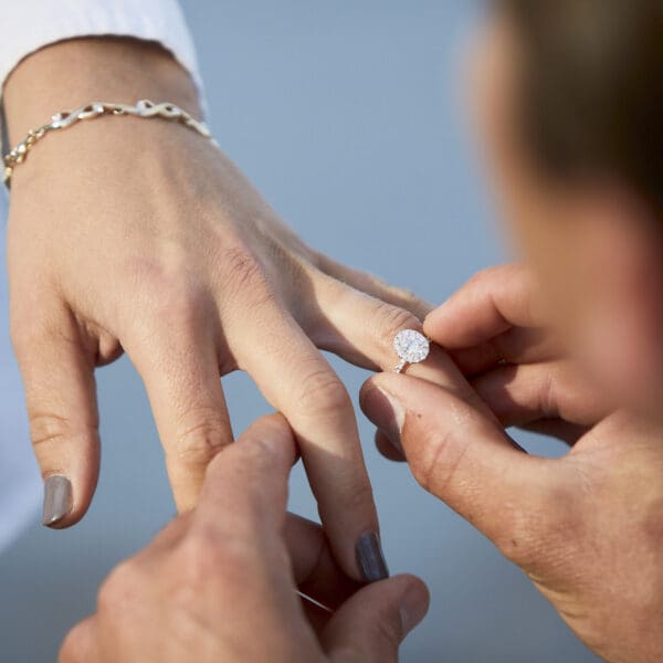 Man placing wedding band or engagement ring on woman's hand