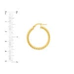 Twisted rope hoop earrings with a ruler for scale.