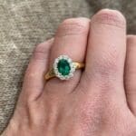 Oval emerald halo ring in 18K two-tone gold with yellow gold band and diamonds, size 6.5.