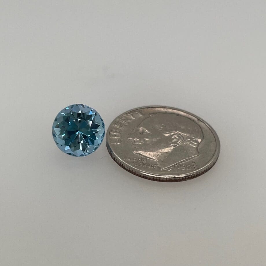 Aquamarine loose with a dime for scale