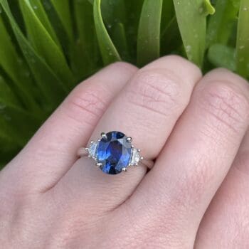 Platinum ring with oval blue sapphire center and trellis Cadillac-cut diamond accents, size 6.5