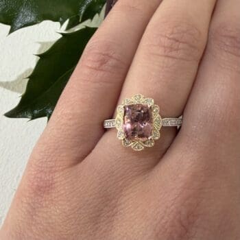 Halo ring featuring a light pink tourmaline center and elongated cushion cut diamonds set in 14K two tone gold
