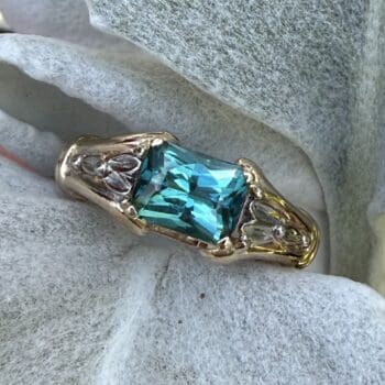 14K two tone ring featuring indicolite blue tourmaline center gem and radiant cut diamonds