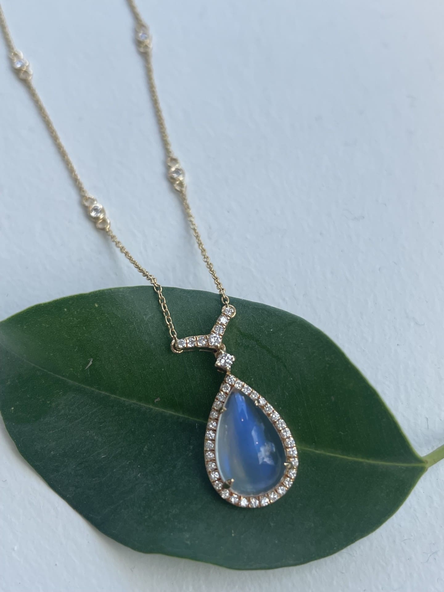 18K yellow gold necklace with a pear cut Blue Rainbow Moonstone and diamond halo on adjustable chain